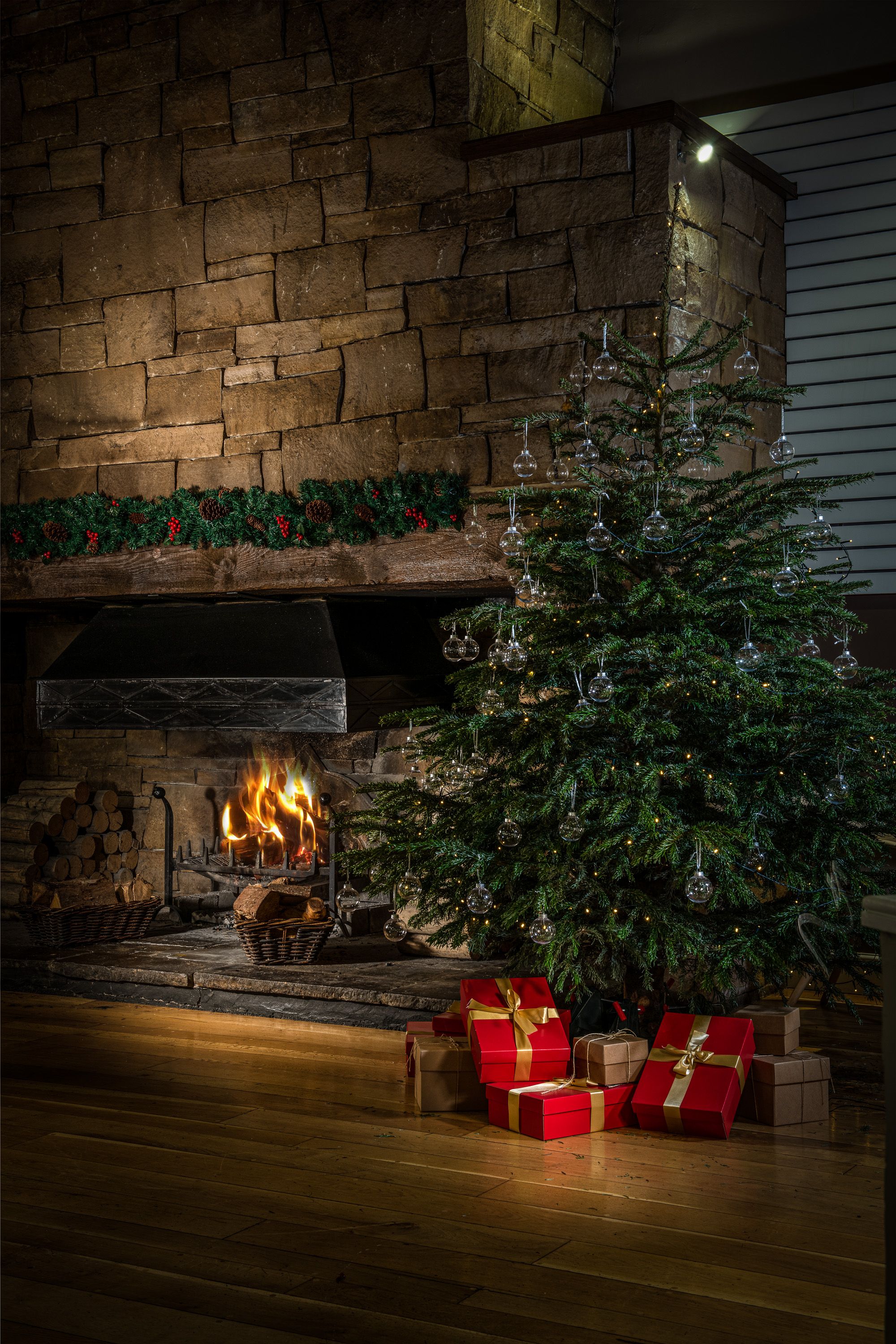 A Christmas tree with presents, close to a fireplace